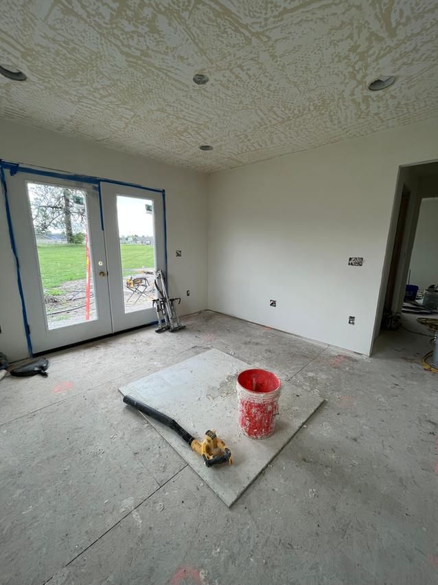 Interior room under construction with white walls, French doors, and construction materials on the floor.