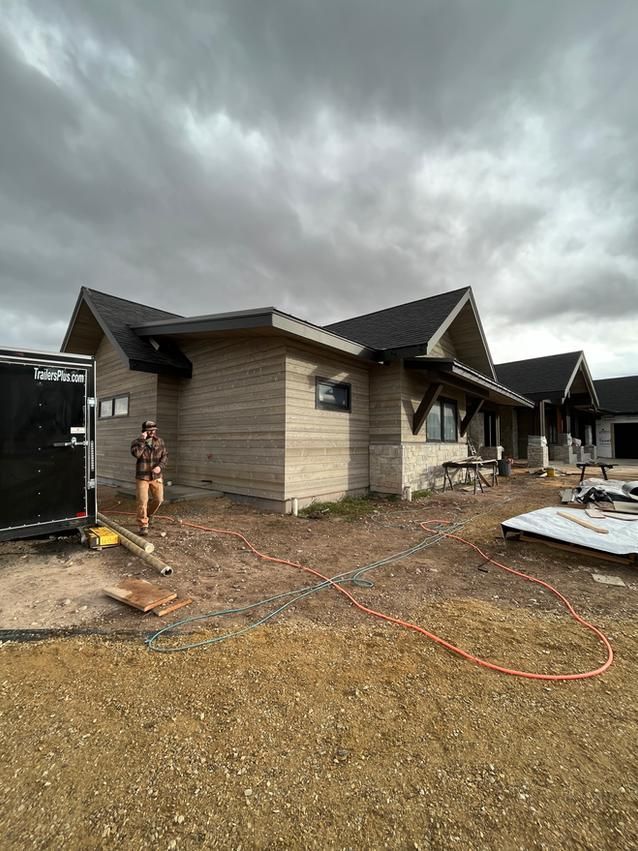 Construction site with a partially built building, worker, and cloudy sky.