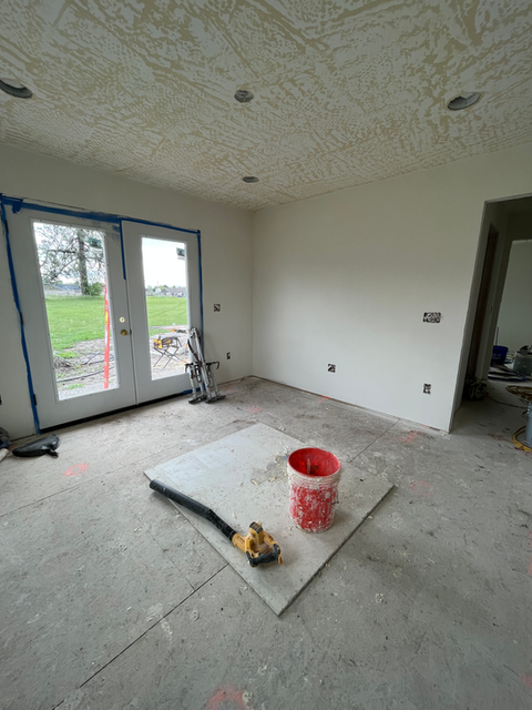 An empty room with a bucket of paint on the floor