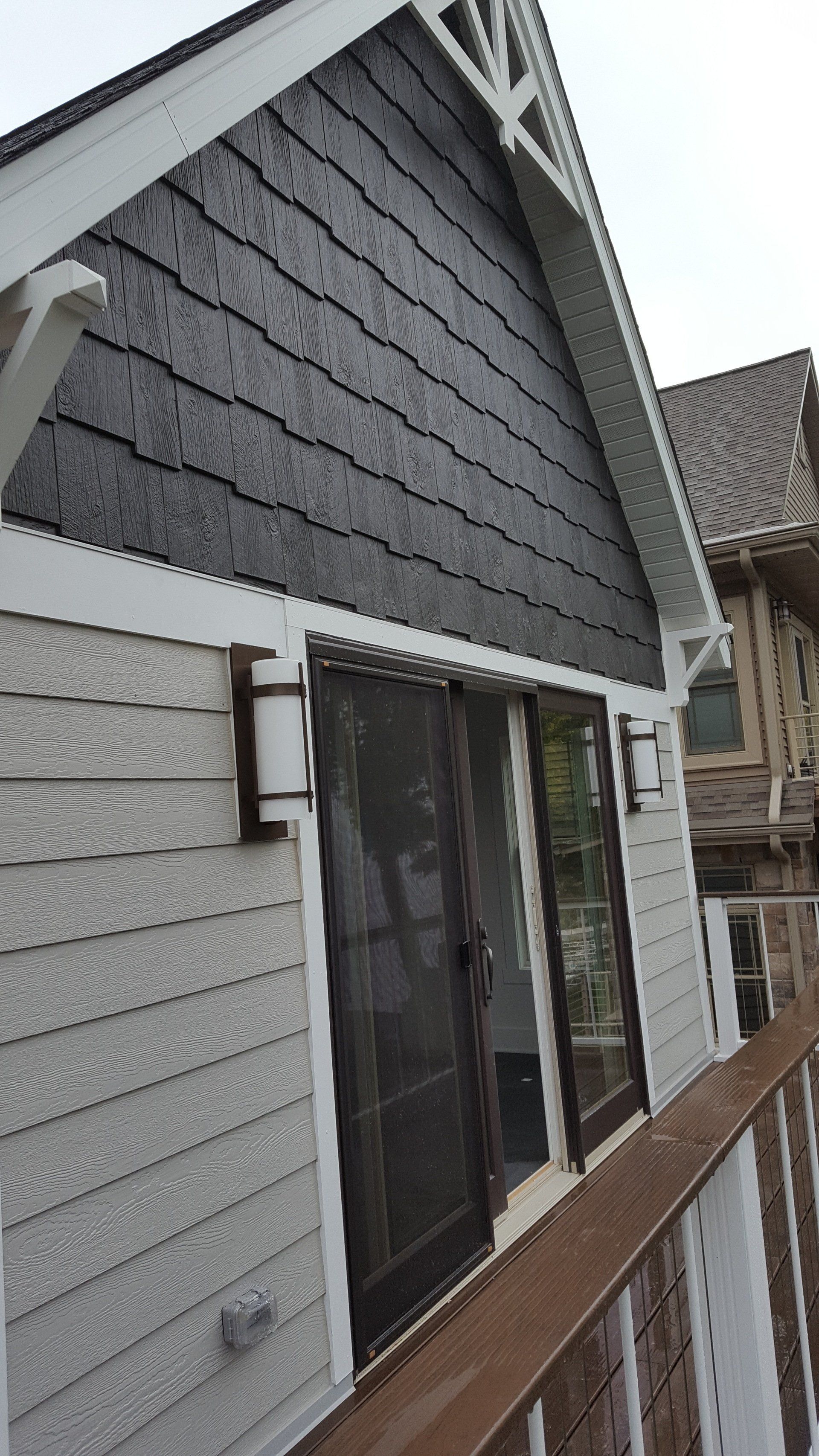 A black and white house with a balcony and sliding glass doors.
