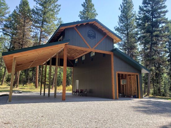 A large building with a carport underneath it is surrounded by trees.