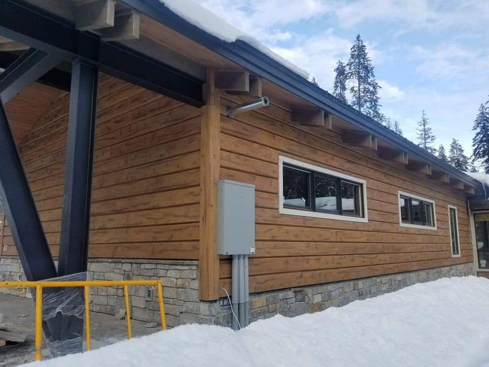 Building with wooden siding and stone base in a snowy setting.