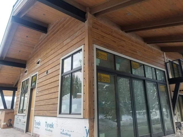 Wooden house exterior with large windows and black frames; light brown siding.