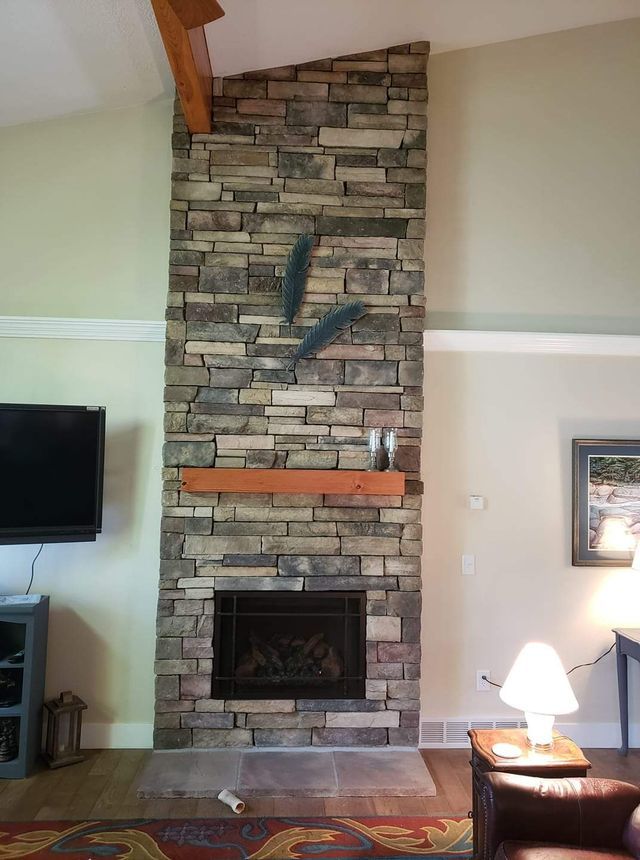 A living room with a stone fireplace and a flat screen tv