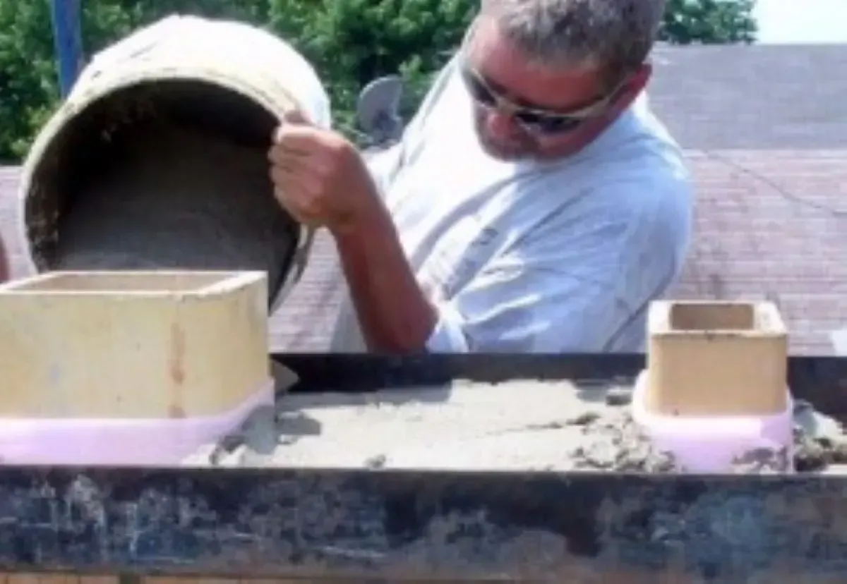 A man is pouring concrete into a container