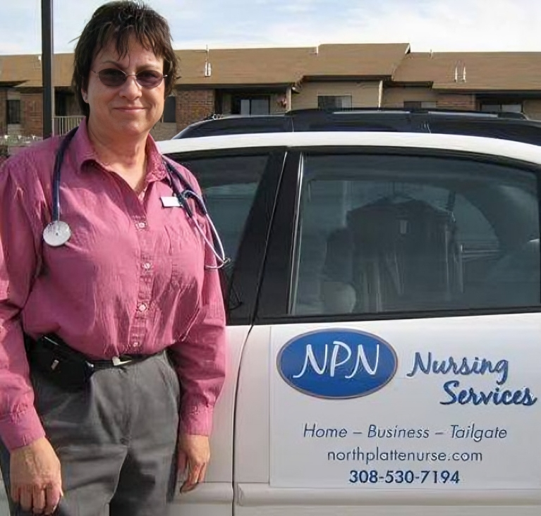 A woman with a stethoscope standing in front of a car that says npn nursing service