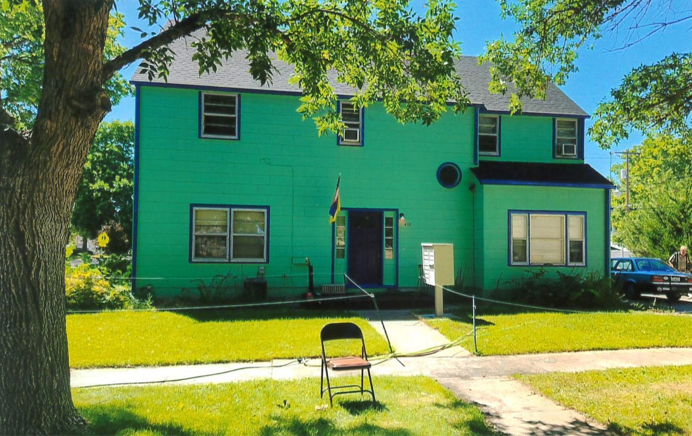 A green house with a chair in front of it