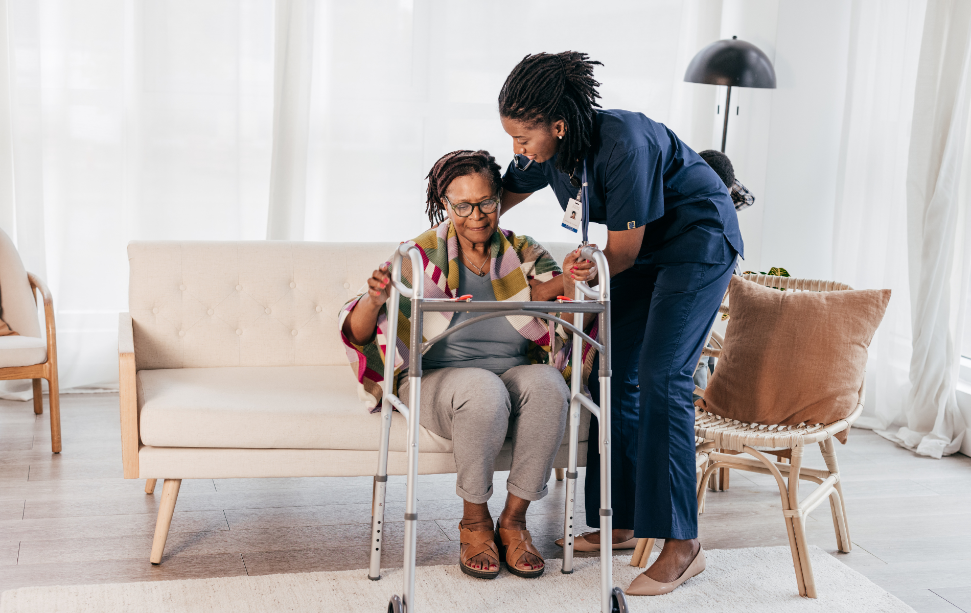A nurse is helping an elderly woman with a walker.