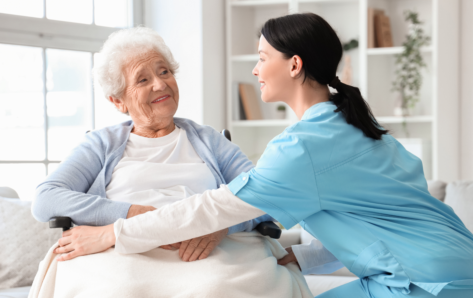 A nurse is talking to an elderly woman in a wheelchair.