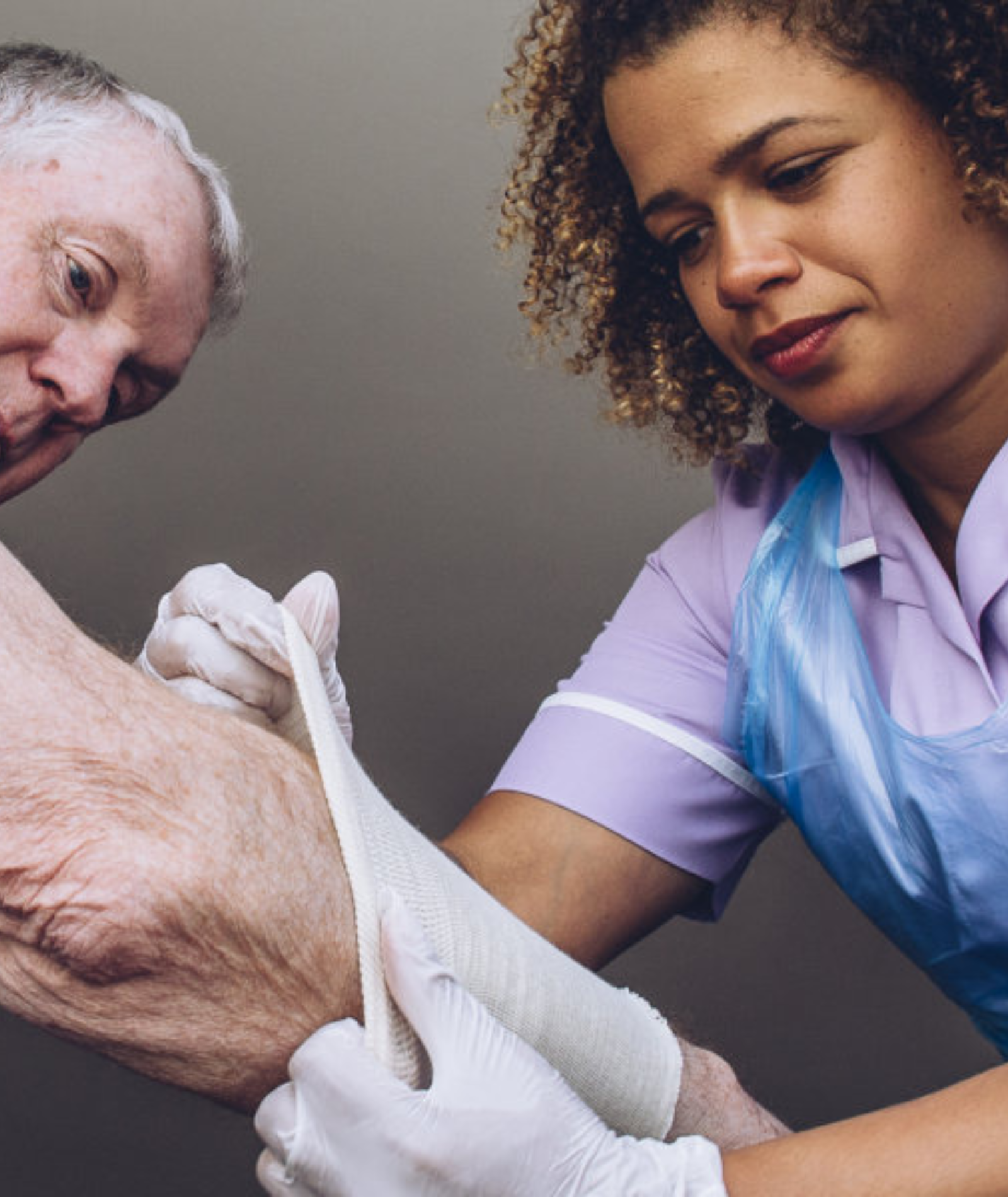 A nurse is putting a bandage on an older man 's arm