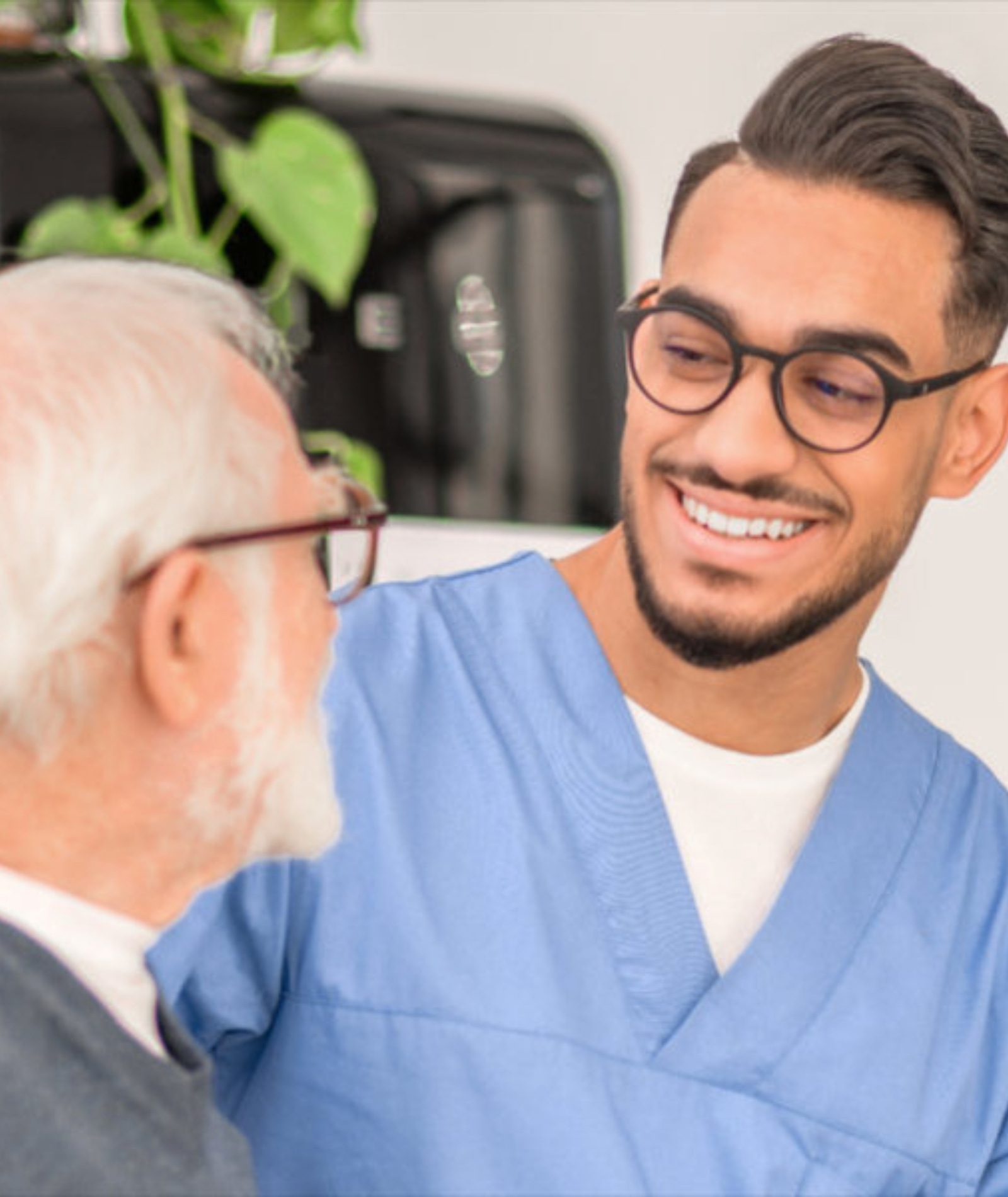 A nurse is smiling while talking to an older man.