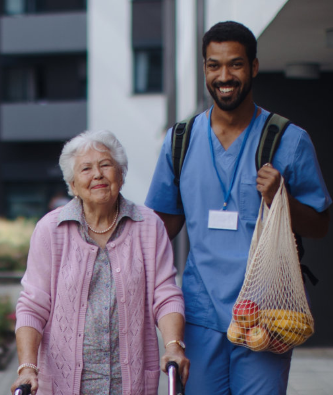 A man is helping an elderly woman with a walker