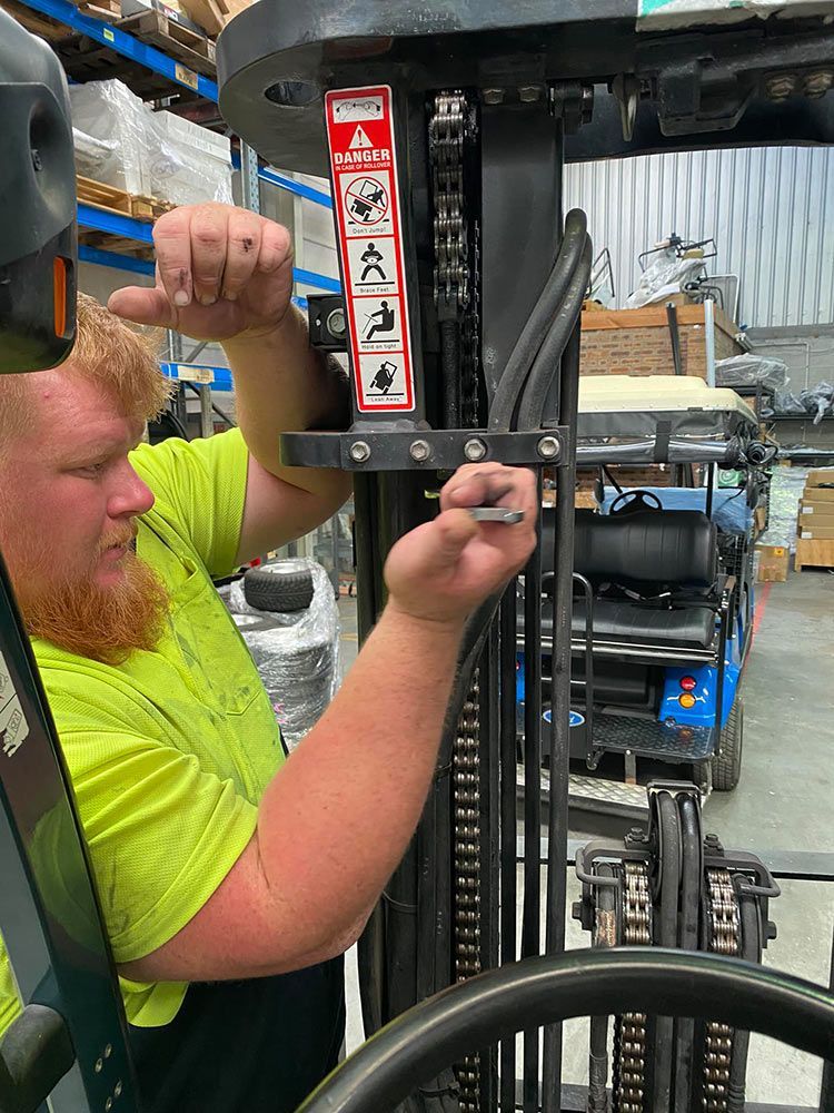 A Man Is Working On A Forklift In A Warehouse — Lift It Equipment in Summerland Point, NSW