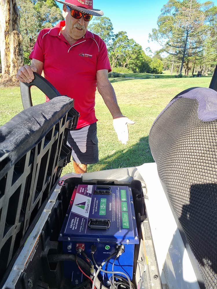 A Man In A Red Shirt Is Standing Next To A Golf Cart — Lift It Equipment in Summerland Point, NSW