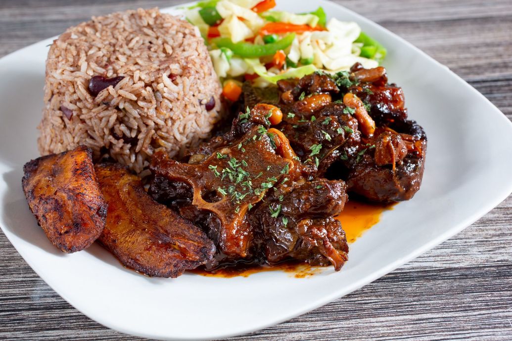A white plate topped with meat , rice and vegetables.