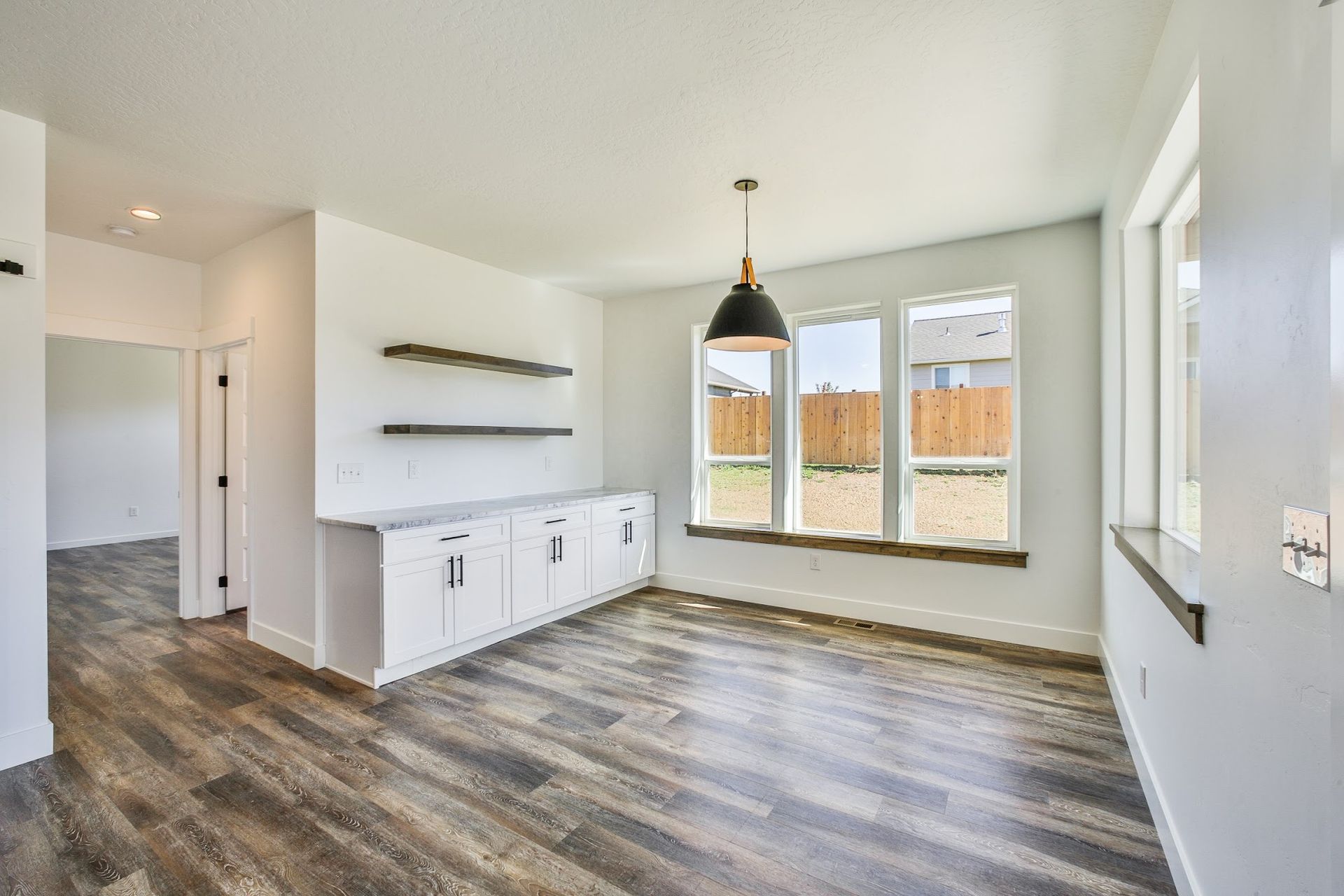 An empty living room with hardwood floors and white walls.