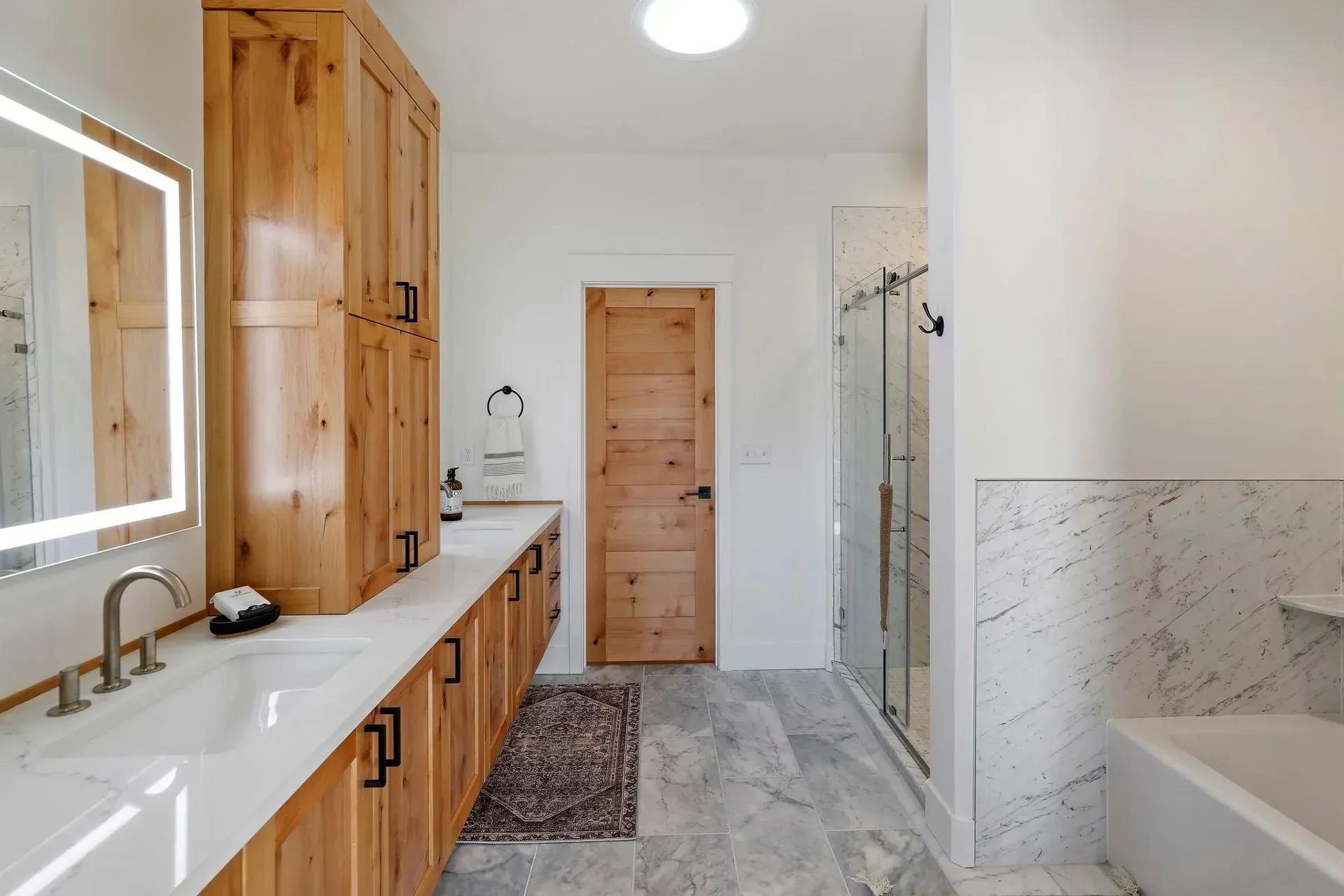 A bathroom with two sinks , a tub and a mirror.