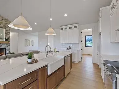 A kitchen with white cabinets , a sink , a stove , and a fireplace.