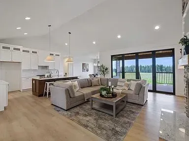 A living room with a large sectional couch , coffee table , and sliding glass doors.