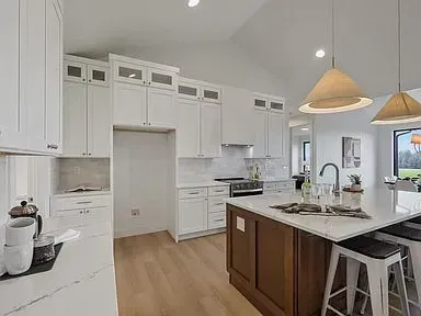 A kitchen with white cabinets and a large island.