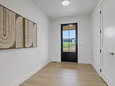 A hallway with a black door and two paintings on the wall.
