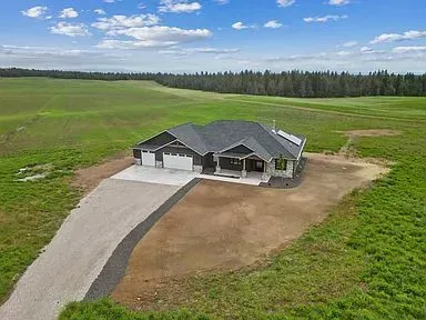 An aerial view of a house in the middle of a grassy field.