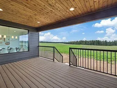 There is a large deck with a view of a field.