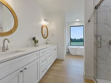 A bathroom with a tub , sink , mirror and shower.