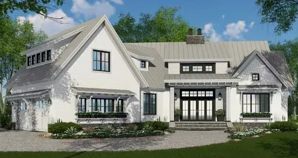 A white house with a gray roof and black windows is sitting on top of a lush green field.