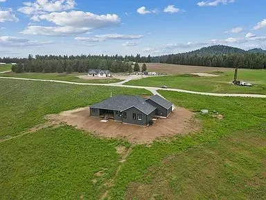 An aerial view of a house in the middle of a grassy field.