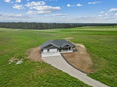 An aerial view of a house in the middle of a grassy field.