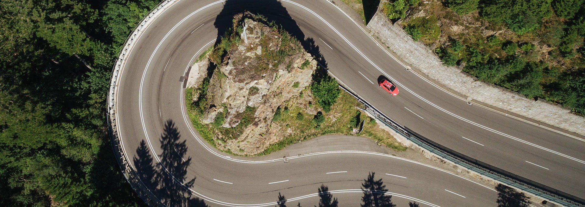 hairpin turn aerial photo with a red car.
