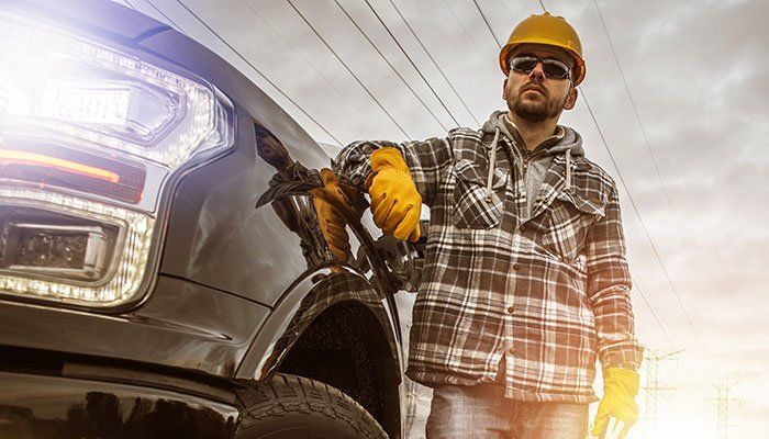 Man wearing hard hat standing next to a truck.