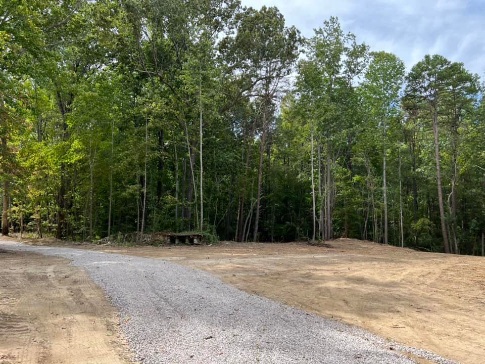 A stone entrance sign for Ivy Glen stands beside a road with a patch of colorful flowers, landscaping, and a utility pole.