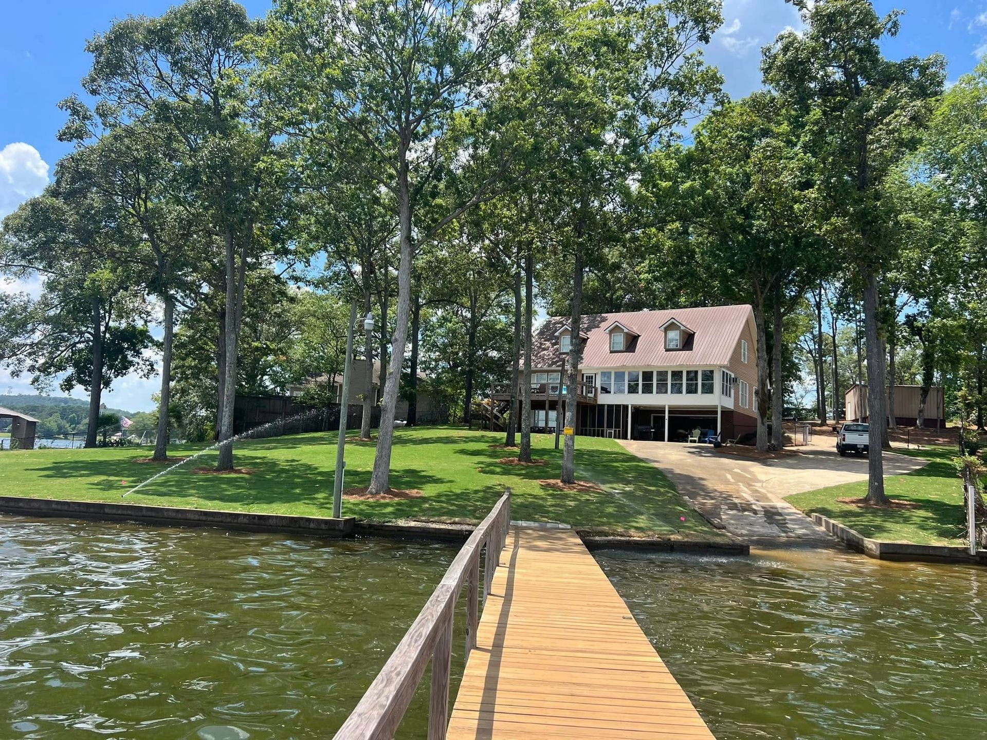 A garden bed with orange marigolds and purple salvia borders a brick path, with trees and a grassy lawn in the background.