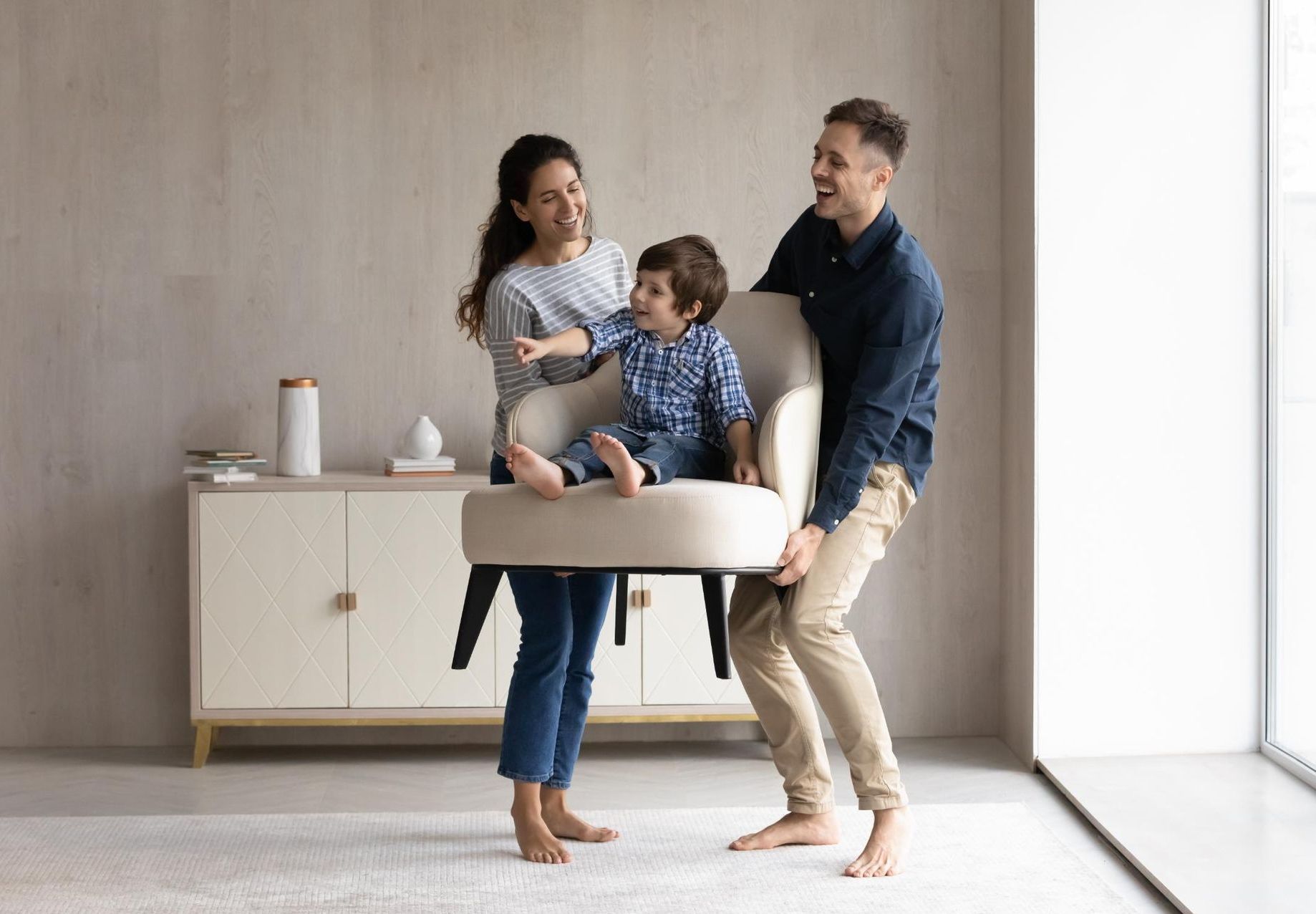 A family is playing with a chair in a living room.