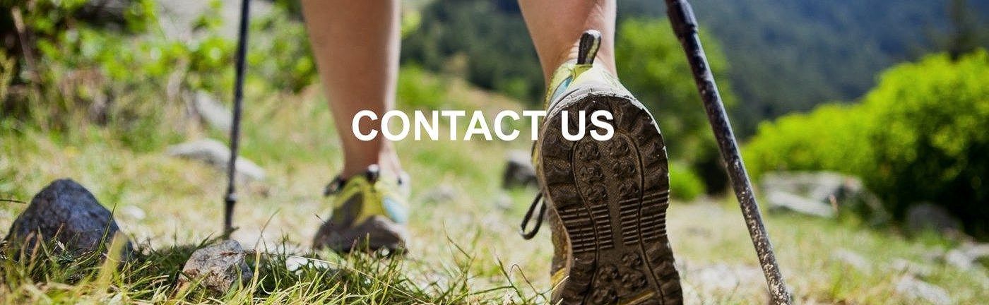 A person is walking on a trail with a hiking pole.