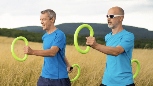 Two men are holding green rings in a field.