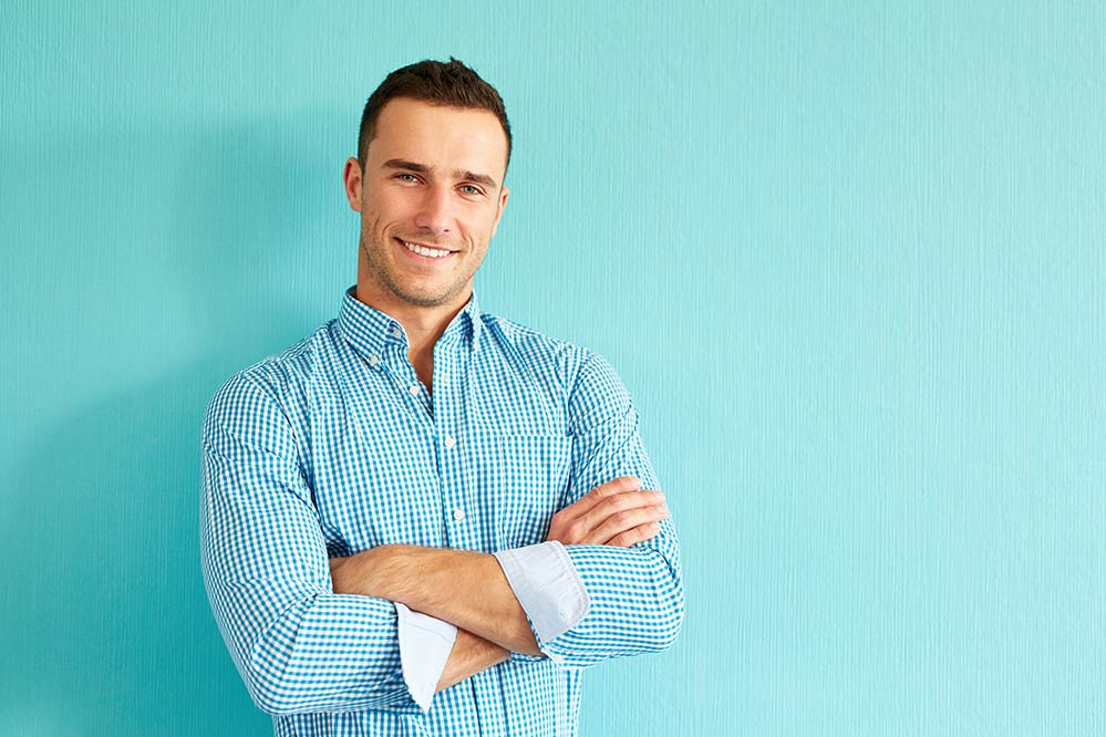 smiling man against light blue wall
