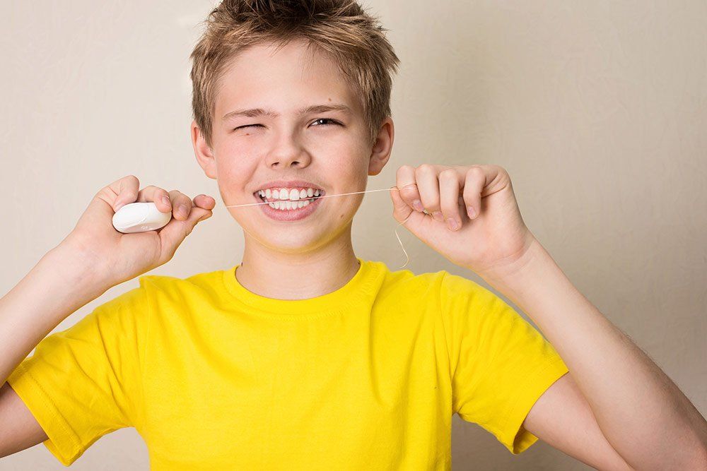 young boy flossing his teeth