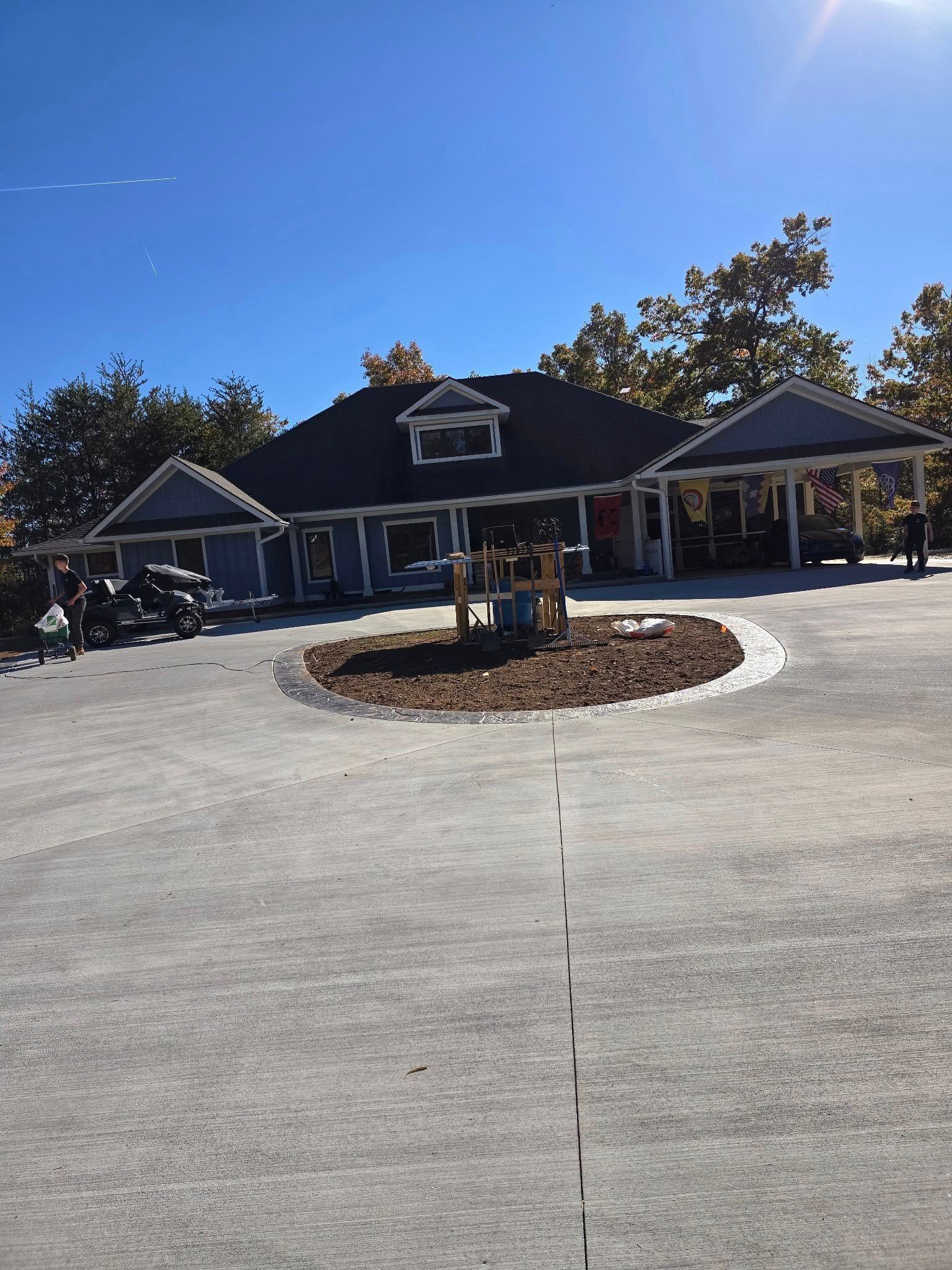 Blue building with a dark roof and carports, on a circular driveway, under a bright blue sky.