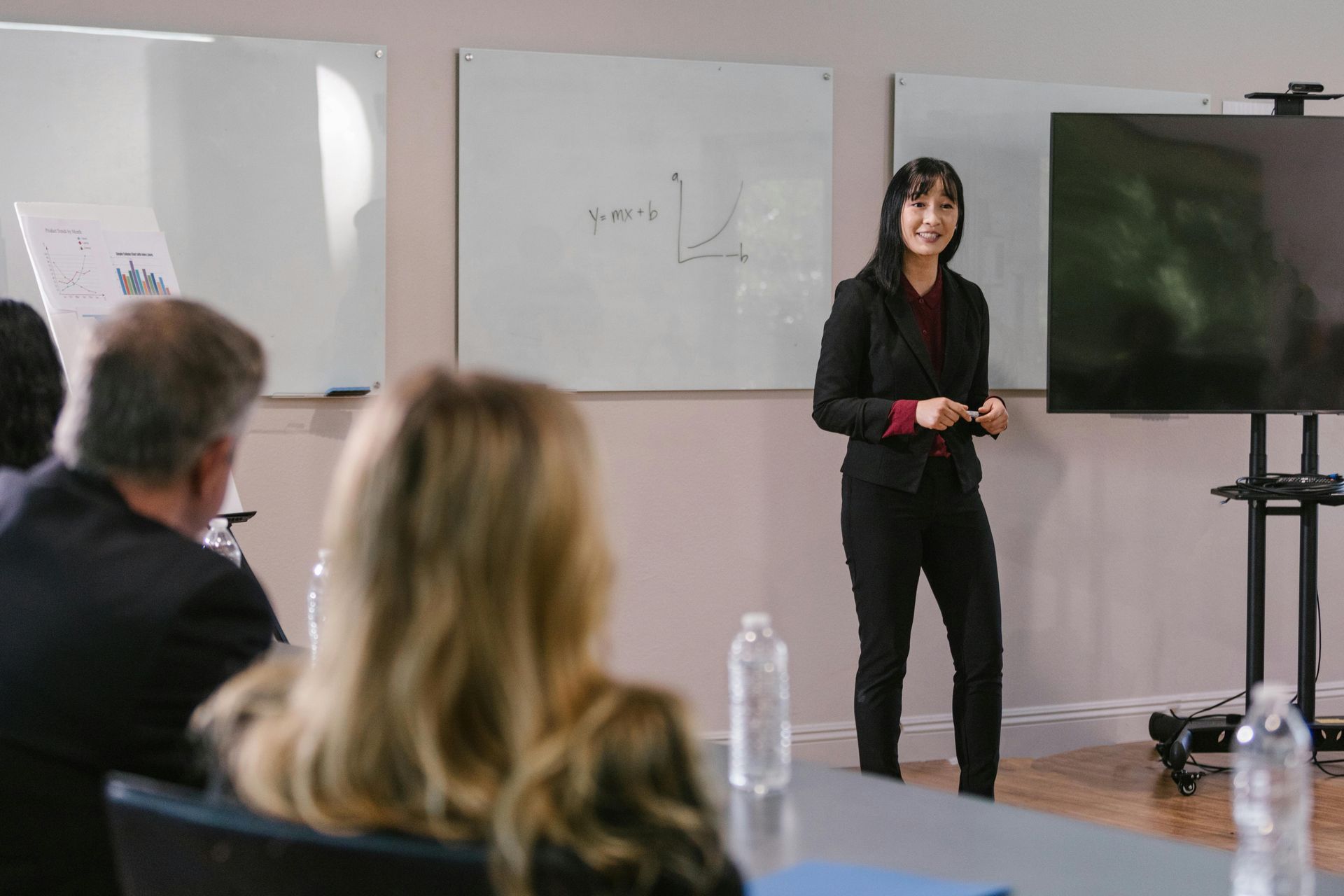 Woman in suit giving a presentation to a small audience in a conference room.