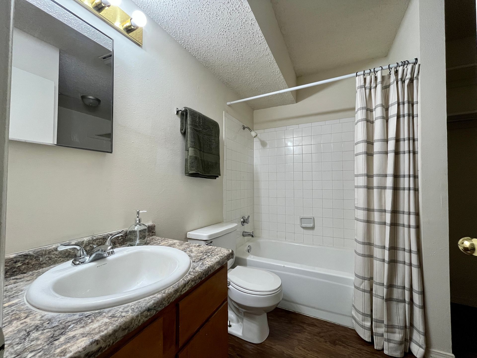 Small white house with porch on a green lawn, under cloudy sky. A garage is in the background.