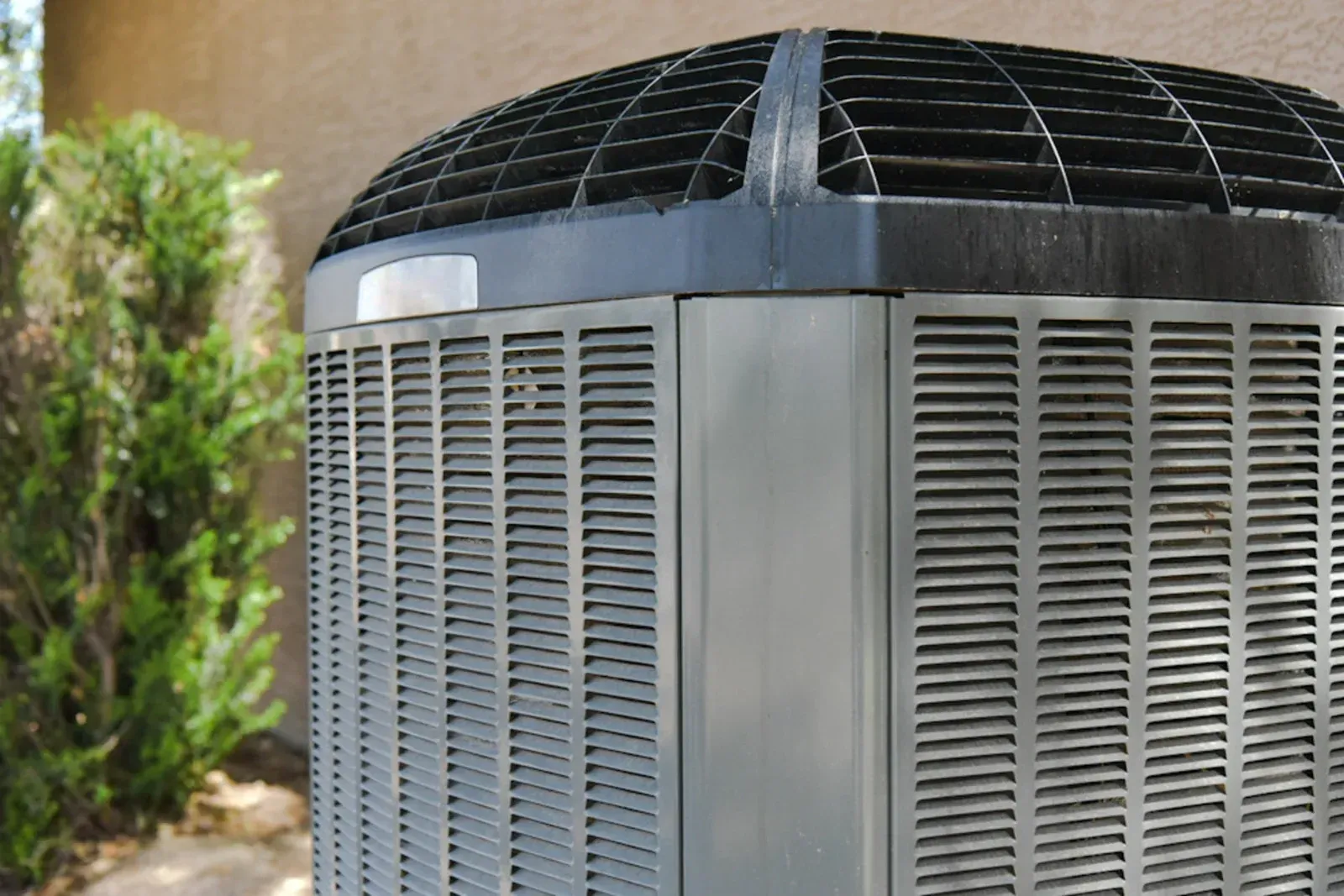 Close-up of a gray outdoor air conditioner unit with a black top grille