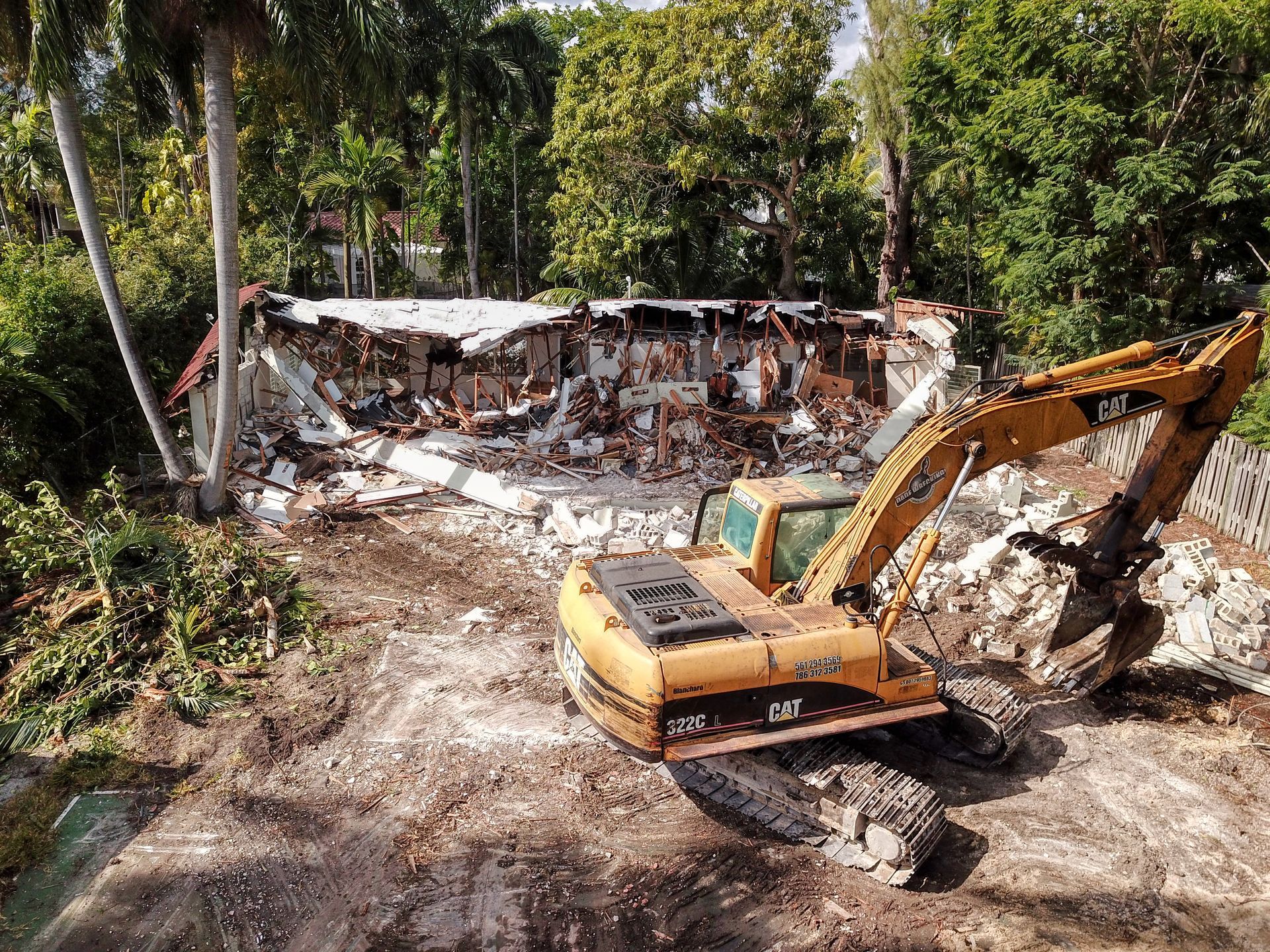 A large yellow excavator is demolishing a building.