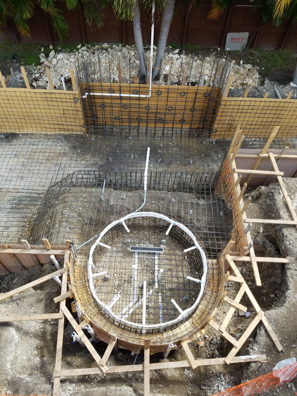 Construction site with wooden forms and metal framework for a curved structure.