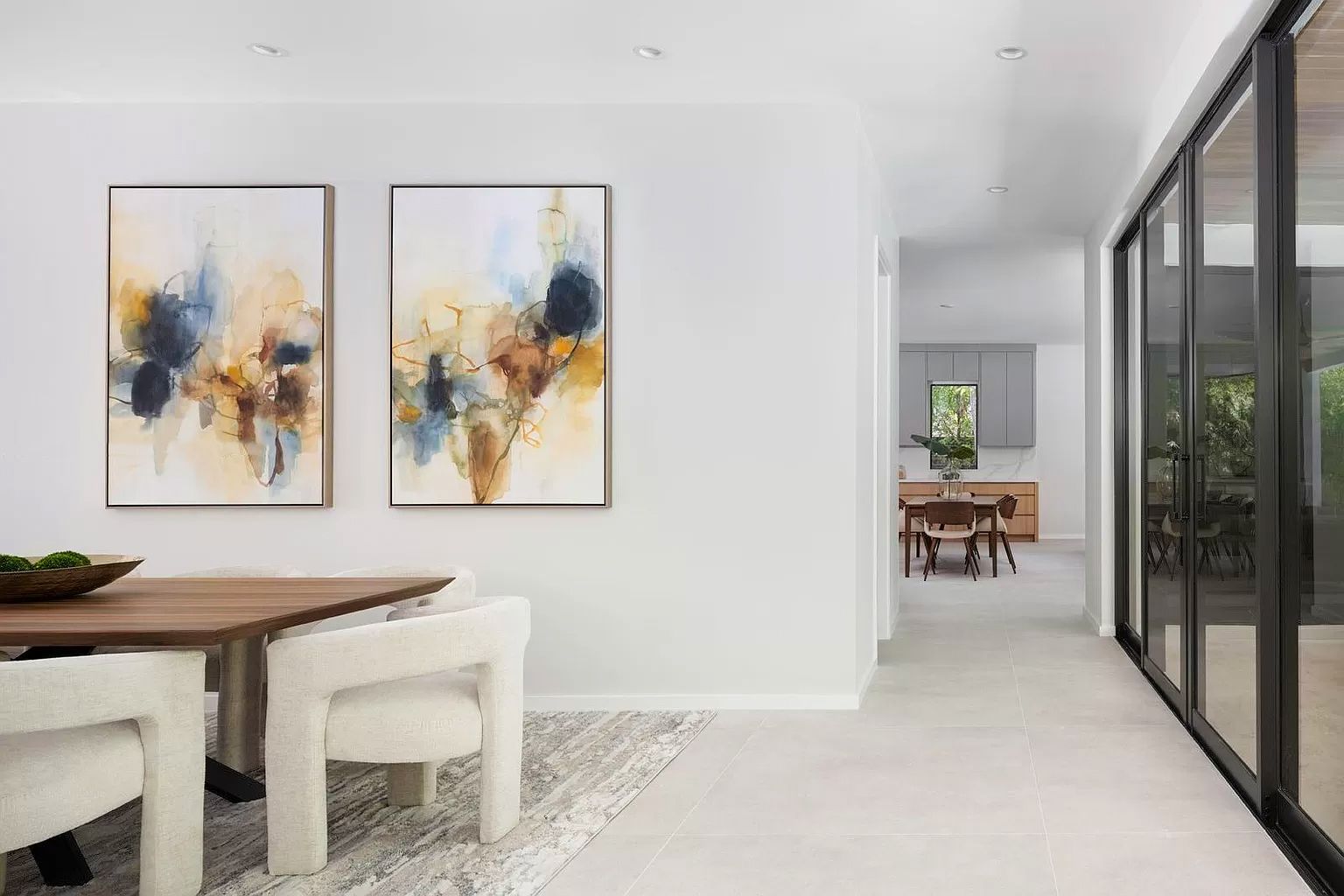 Dining room with abstract art, table with white chairs, and sliding glass doors.