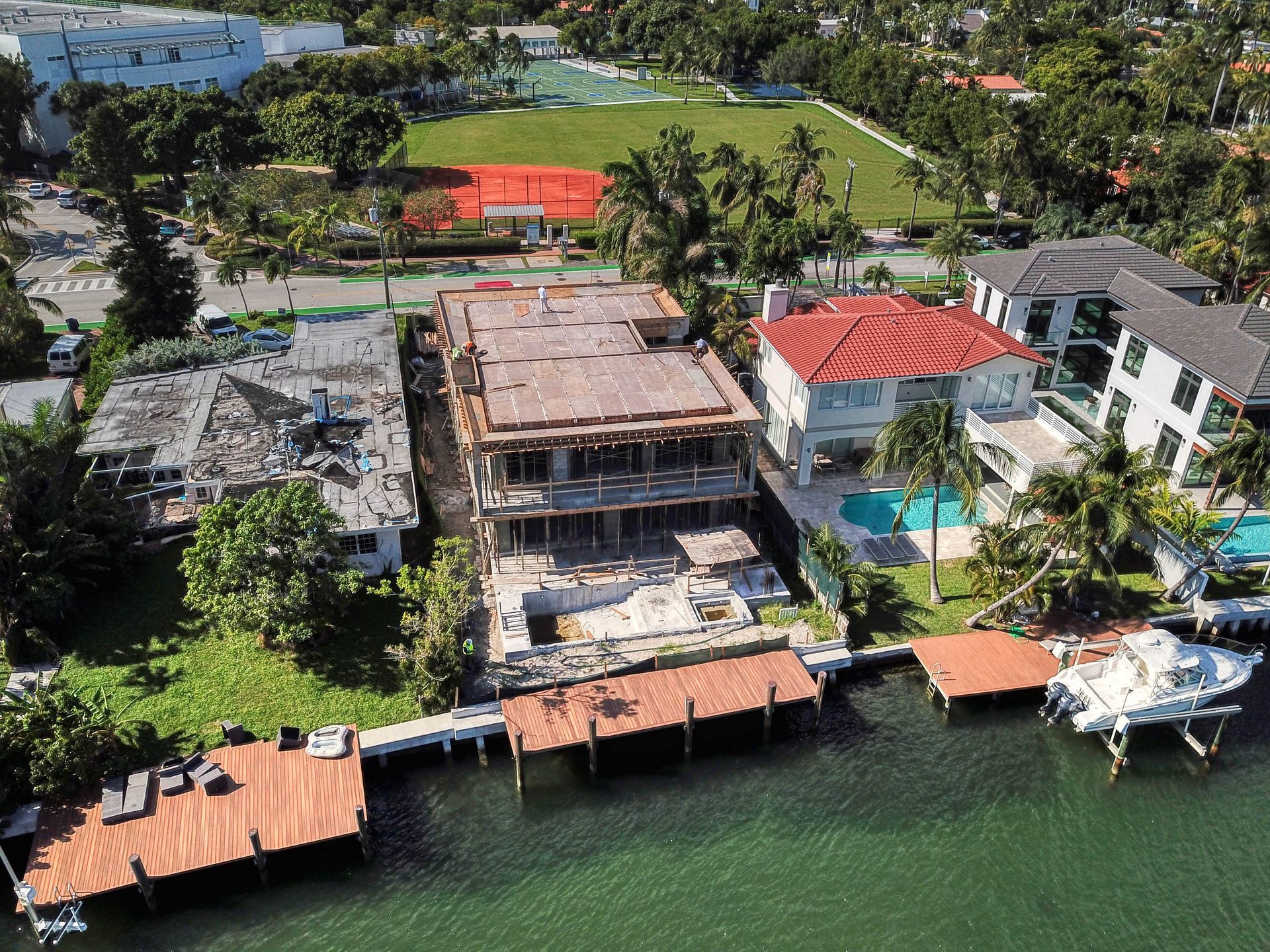 Aerial view of waterfront homes, one under construction, with docks and boats in the water.