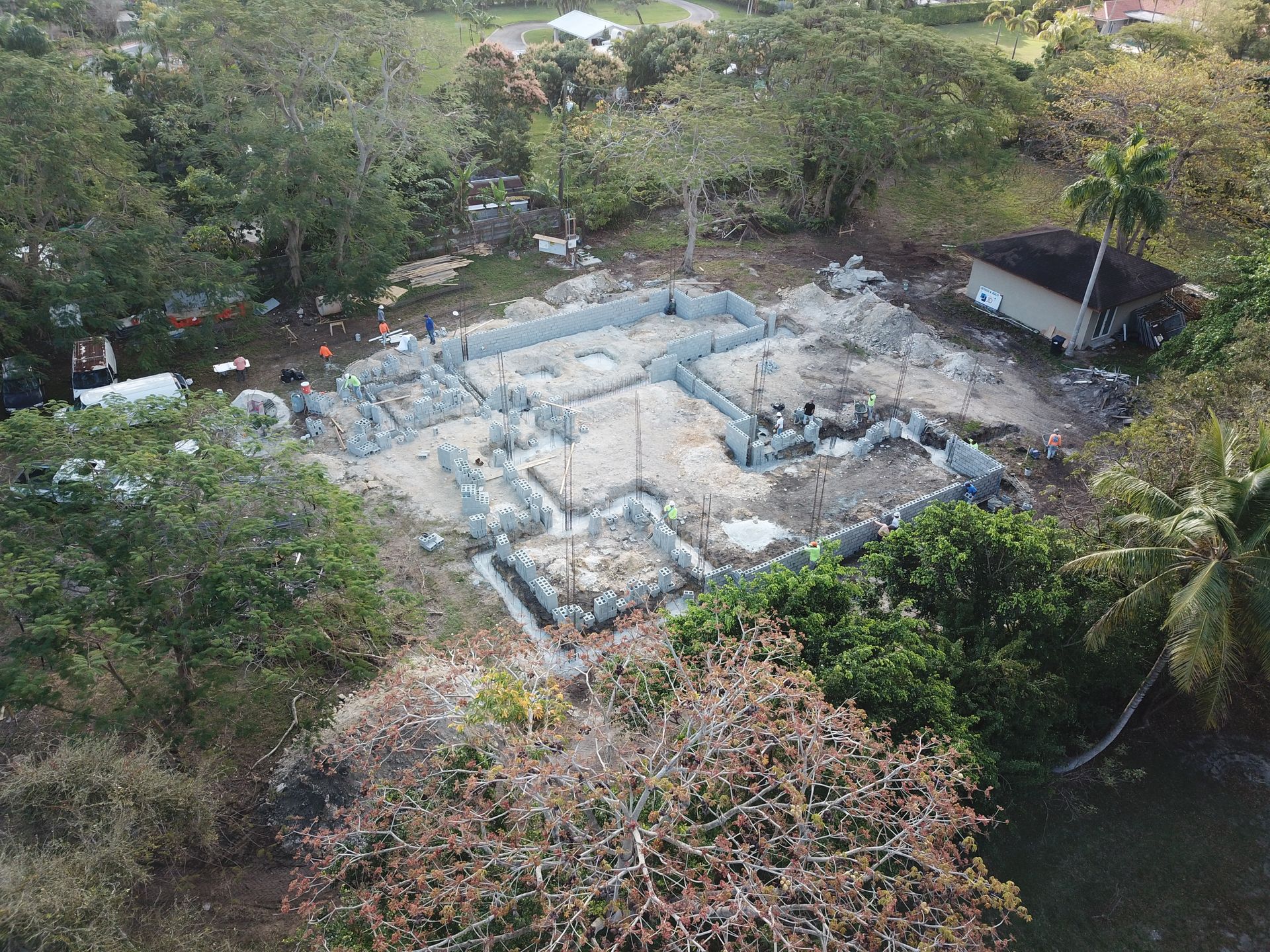 An aerial view of a house under construction in the middle of a forest.