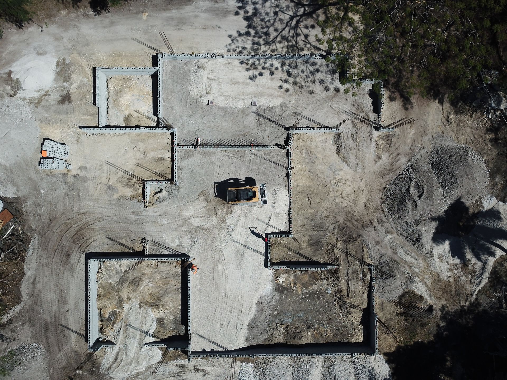 An aerial view of a construction site with a palm tree in the background.